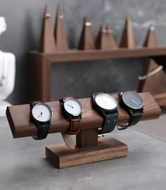 four watches are sitting on a wooden stand