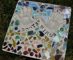 a hand and foot sign made out of sea glass on the grass with words roots wings