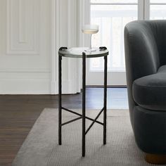 a living room with a gray couch and glass side table on the carpeted floor