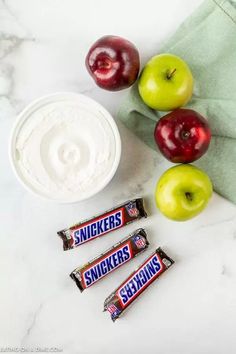 three apples, two snickkers and some yogurt on a table