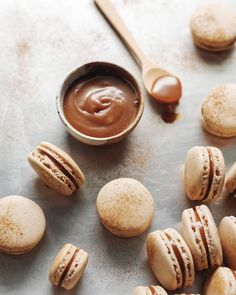 some macaroons are next to a cup of peanut butter