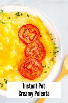 a white bowl filled with mashed potatoes topped with sliced tomatoes and green garnish