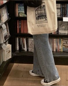 a person standing in front of a book shelf holding a bag