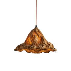 a light that is hanging from a cord on a white wall with a tree stump in front of it