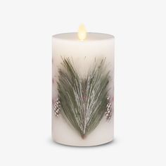 a white candle with some green and silver decorations on the front, in front of a white background