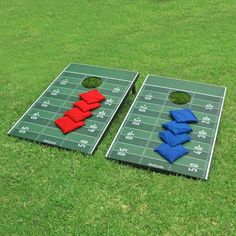 two red and blue bean bag tossers sitting on top of a green football field