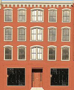 a red brick building with several windows and a fire hydrant in front of it