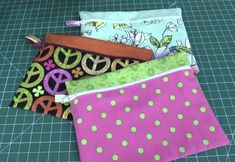 four zippered pouches sitting on top of a cutting board with green and pink polka dots