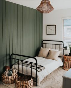 a bedroom with green painted walls and white linens on the bed, two wicker baskets in front of the bed