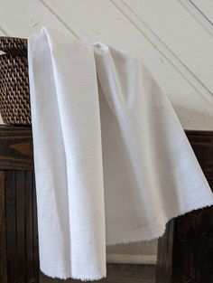 a white towel hanging from the side of a wooden chair