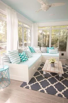 a living room filled with lots of furniture and large windows covered in white drapes