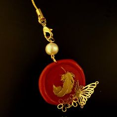 a gold and red pendant with a horse on it's back end, attached to a chain