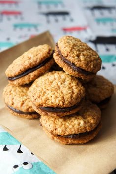 cookies are stacked on top of each other in a brown paper bag, sitting on a patterned tablecloth