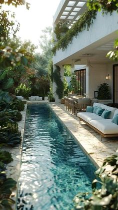 an outdoor swimming pool surrounded by greenery and lounge chairs with white cushions on it