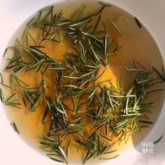 a white bowl filled with green herbs on top of a table