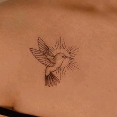 a small bird tattoo on the back of a woman's upper arm and shoulder