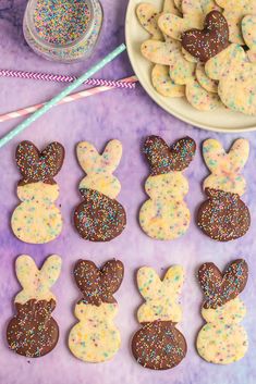 some cookies are shaped like easter bunnies with sprinkles on them next to a bowl of candy