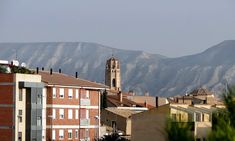 there is a clock tower in the distance with mountains in the backgrouds