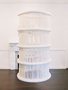 a tall white wicker sculpture sitting on top of a hard wood floor