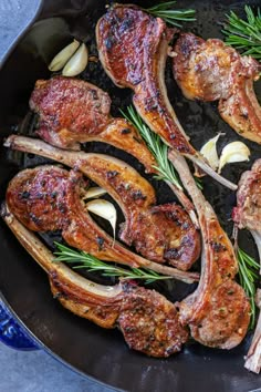 meat and onions cooking in a skillet with rosemary sprigs on the side