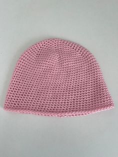 a pink knitted hat sitting on top of a white table