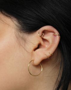 a close up of a person's ear with two gold hoops on it