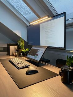 a laptop computer sitting on top of a wooden desk next to a monitor and keyboard