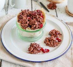 a plate topped with chocolate and cherries next to a glass bowl filled with granola