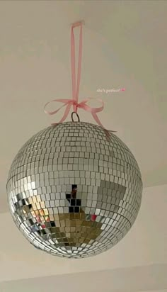 a disco ball hanging from the ceiling with a pink ribbon