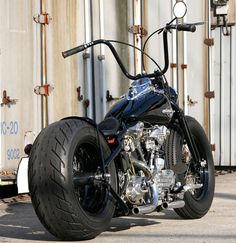 a black motorcycle parked in front of a building next to a white trailer with metal pipes on it