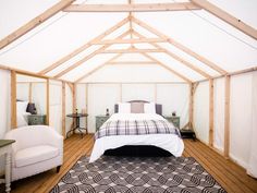 a bed sitting inside of a bedroom on top of a hard wood floor next to a white chair