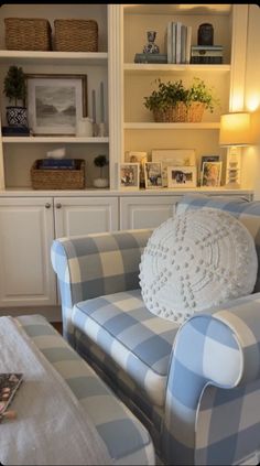 a blue and white checkered couch sitting in front of a book shelf filled with books