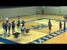 some girls are playing volleyball on a court with blue and white colors in the gym