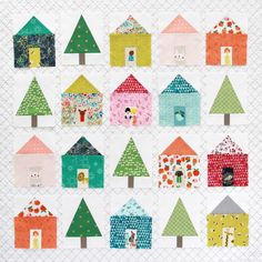 a quilted wall hanging with small houses and trees on the front, in various colors