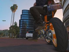 a man riding on the back of a motorcycle next to tall buildings and palm trees