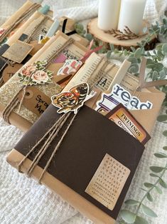 an envelope with some tags attached to it sitting on a table next to candles and greenery