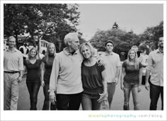 a black and white photo of people walking down the street with their arms around each other