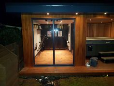 the inside of a small wooden building with glass doors and wood flooring at night