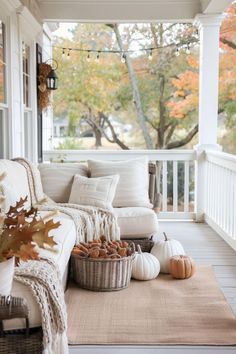 a porch with white furniture and fall decorations