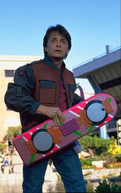 a man holding a skateboard in front of a building