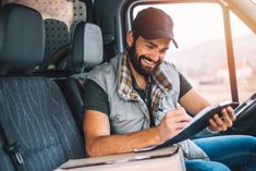 a man sitting in the driver's seat of a truck holding a clipboard