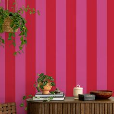 a pink and red striped wall next to a table with a potted plant on it