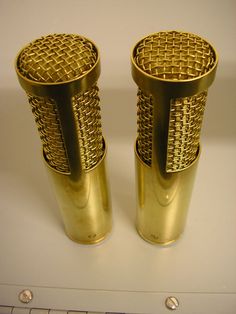 two gold colored metal cups sitting on top of a white counter next to a keyboard