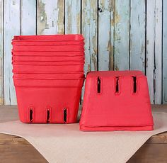 several red plastic containers stacked on top of each other in front of a wooden wall