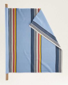 a blue and red striped blanket folded on top of a wooden stick next to a white wall