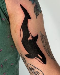 a woman with a tattoo on her arm has an orca whale in it's back