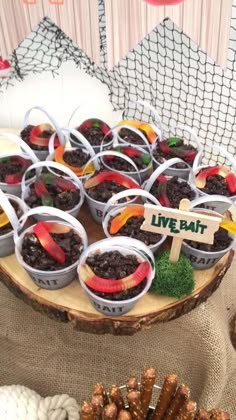 a table topped with lots of desserts on top of a wooden tray covered in dirt