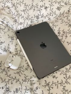 an apple ipad is sitting on a bed with headphones and earbuds next to it