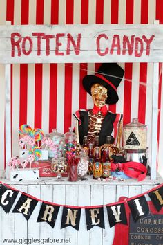 a table topped with lots of candy next to a red and white striped sign that says rotten candy