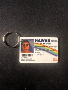 a close up of a person's identification card on a key chain with a rainbow in the background